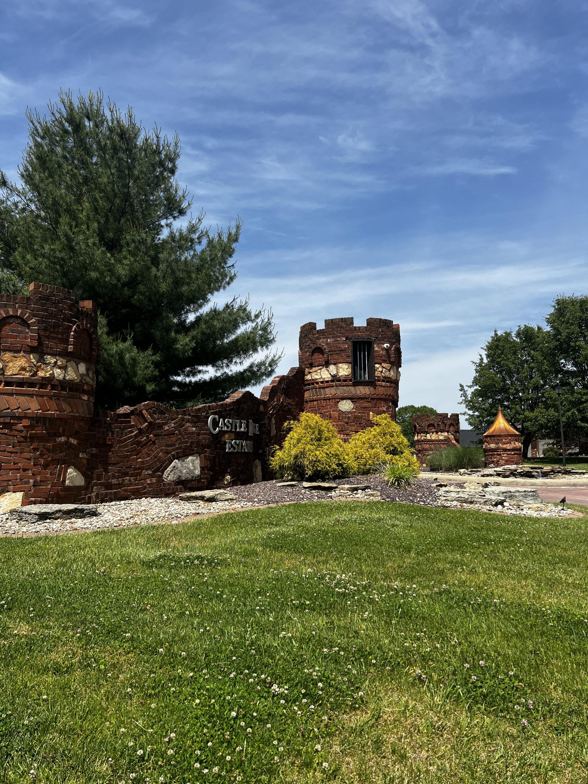 Stately red brick, stone and cooper subdivision entry with castle like design.