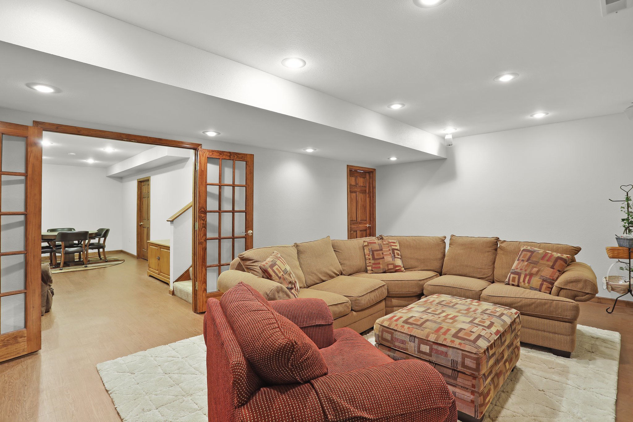 Home features a family room, french doors, couches and vinyl plank wood-like tile flooring