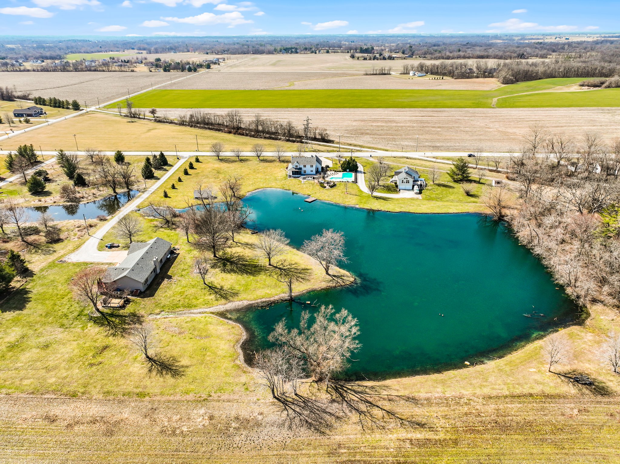 Aerial view of backside of property-acreage, home, inground pool, large pond and dock