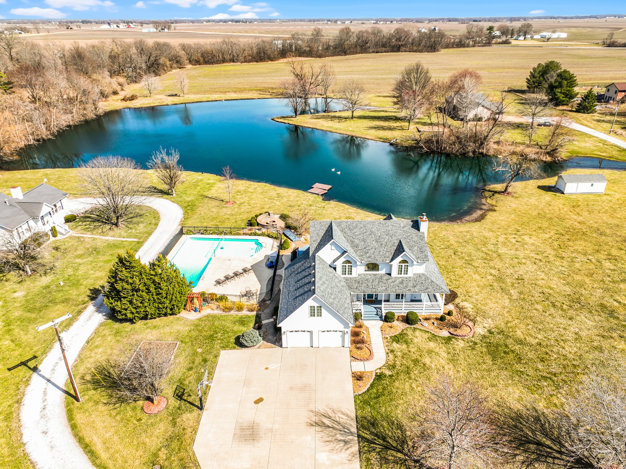 Aerial view of a traditional home, property-acreage, home, inground pool, large pond and dock