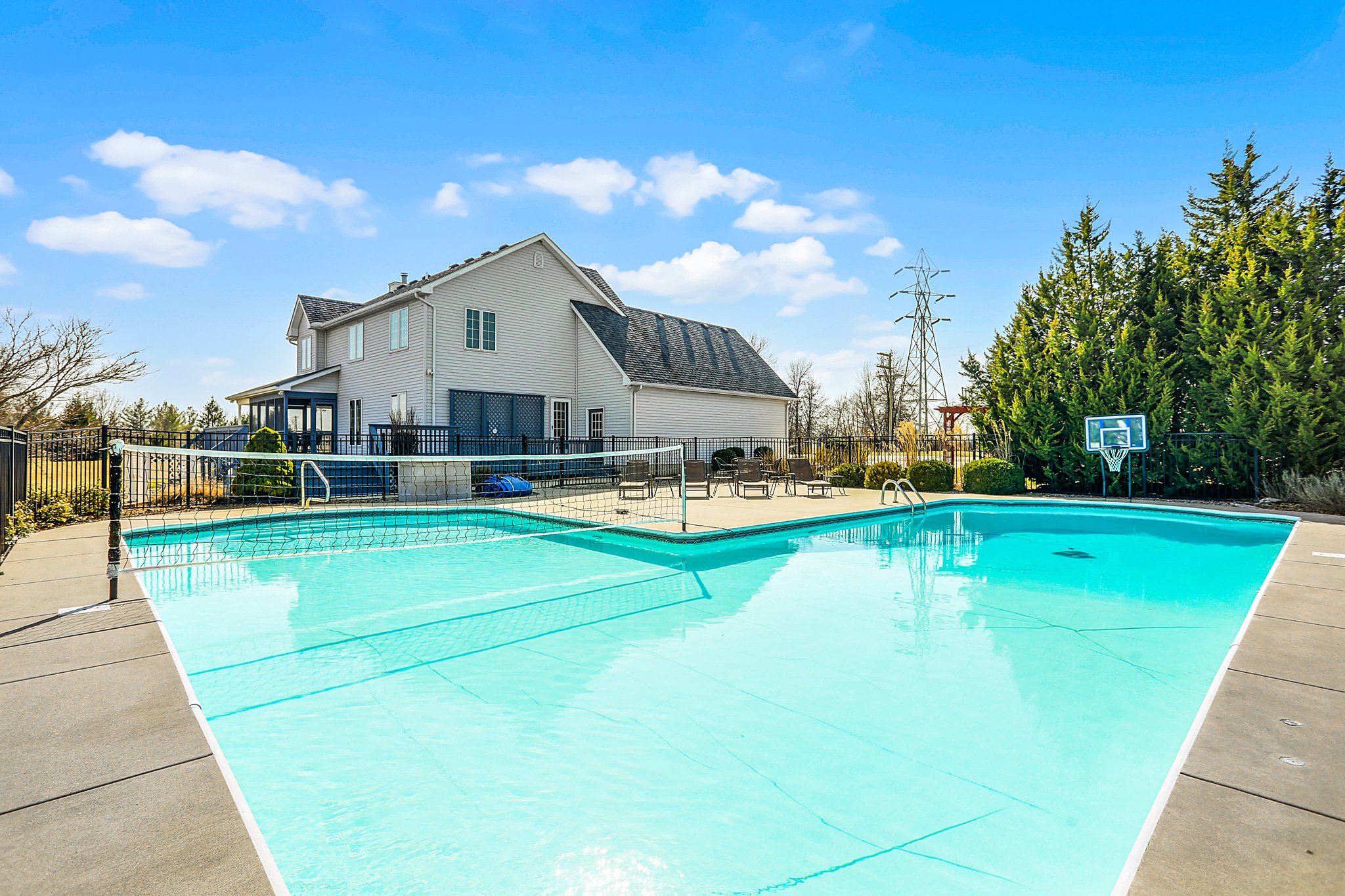 Inground pool with volleyball net, traditional home, and large patio with patio furniture