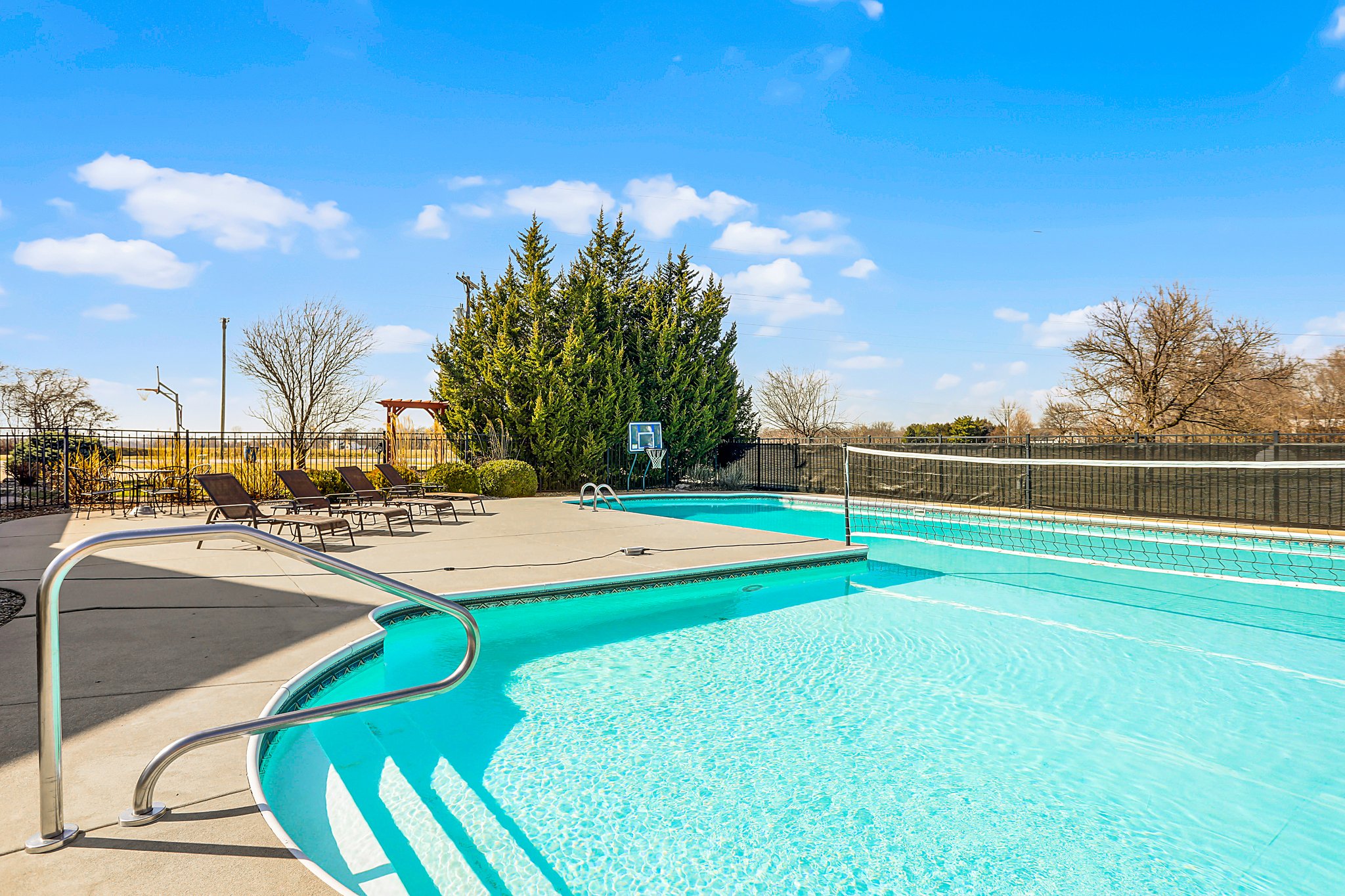 Inground pool with volleyball net and large patio