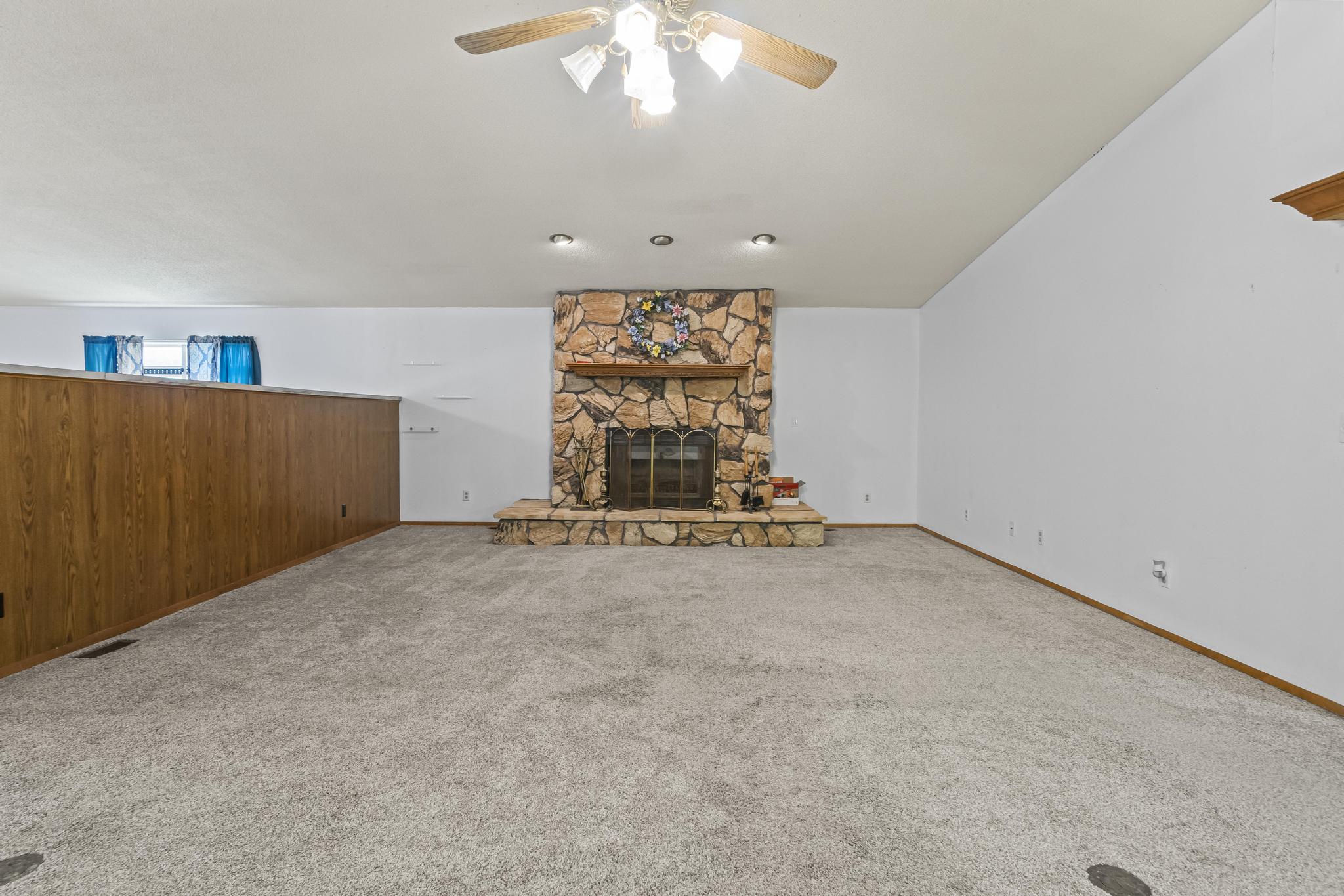Great Room, Stone Wood-burning fireplace, ceiling fan and carpet