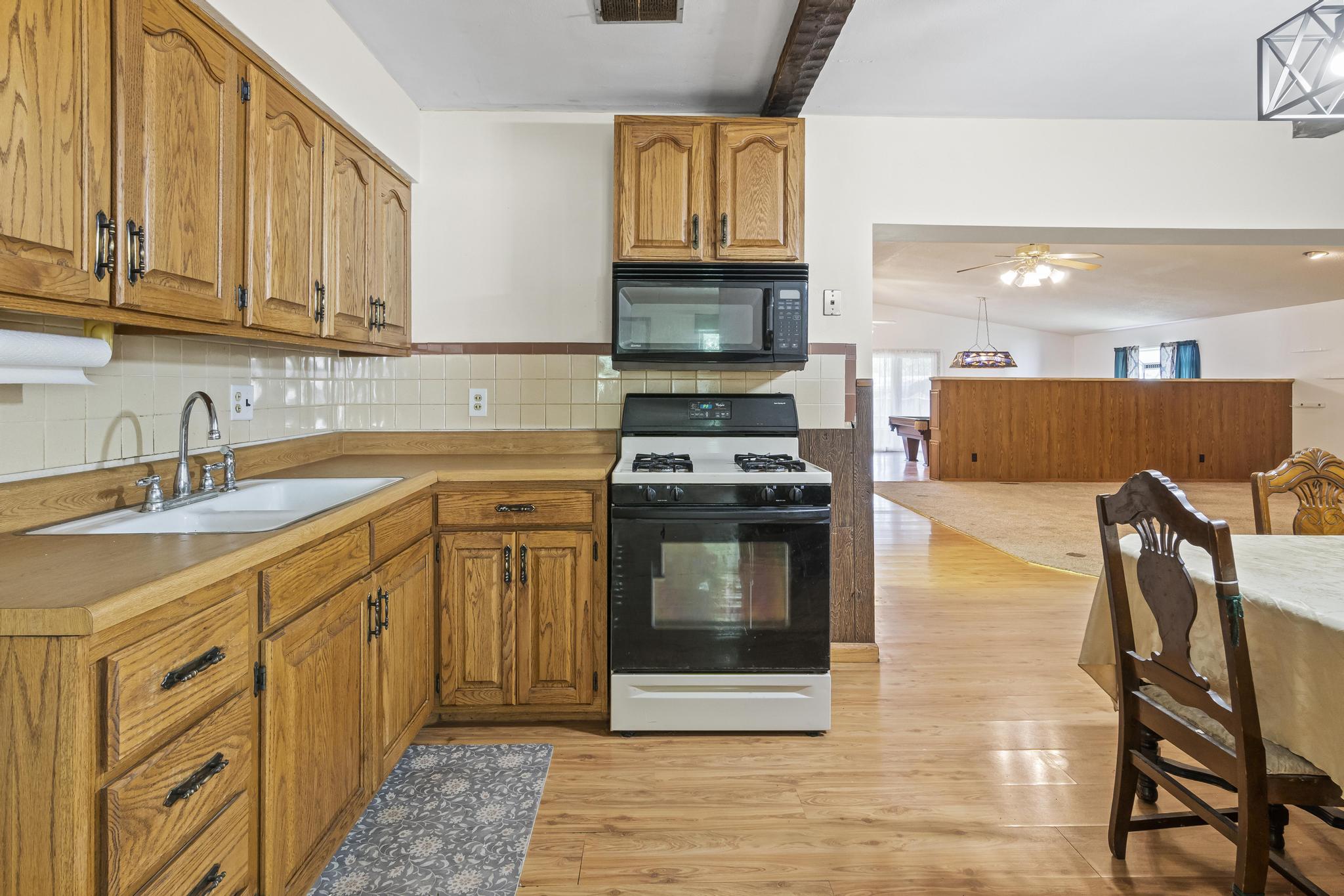 Kitchen, range/oven gas, microwave, laminate wood-style flooring, and ceiling beams
