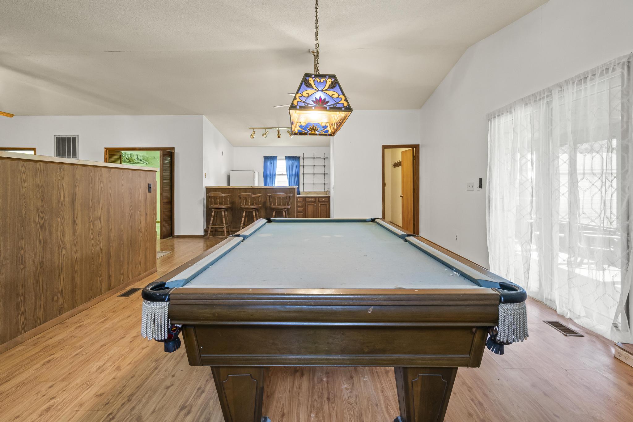 Great room/game room, pool table, Wet bar, and laminated wood-style flooring