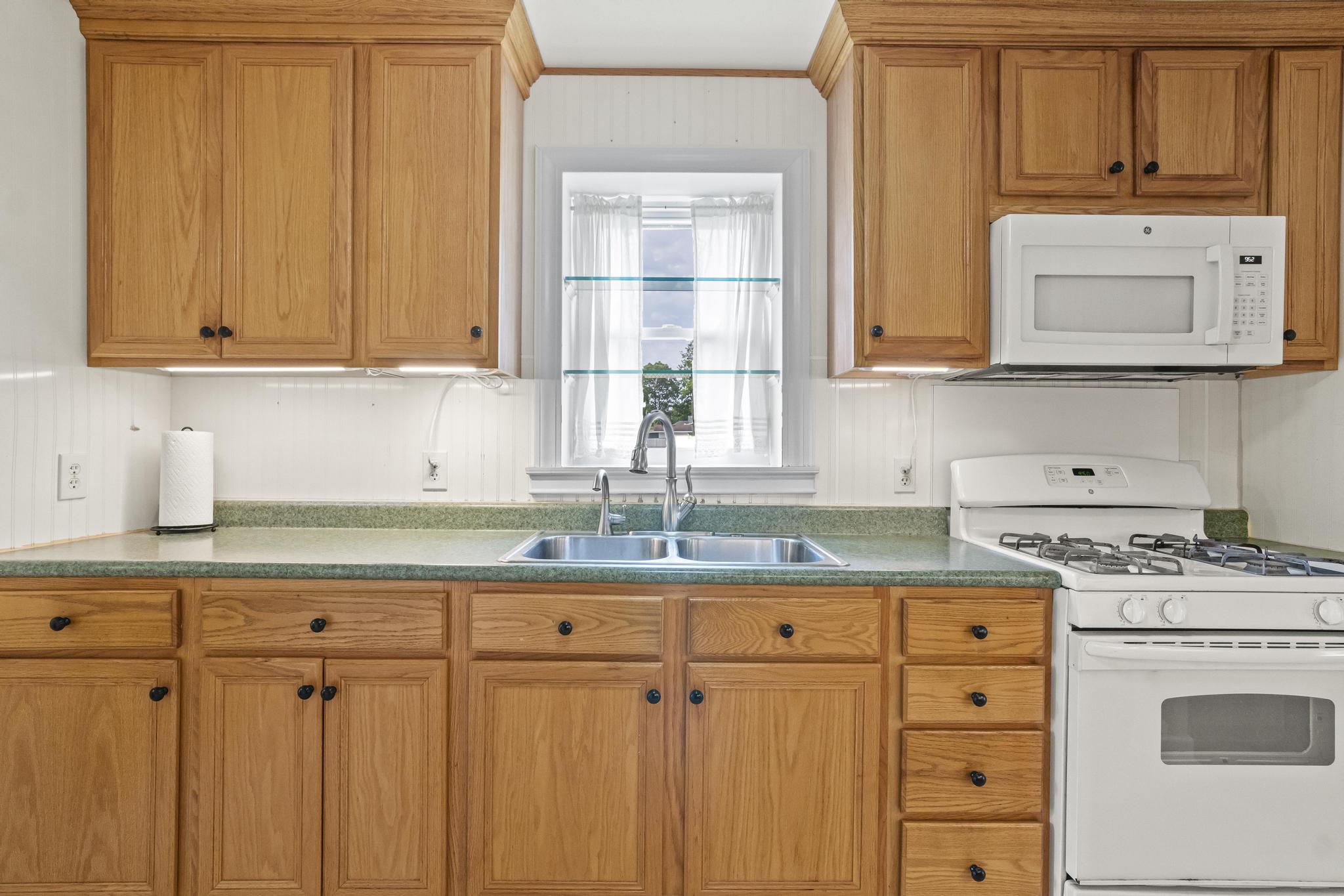 Kitchen with appliances, updated light cabinetry with under cabinet lighting and light colored flooring
