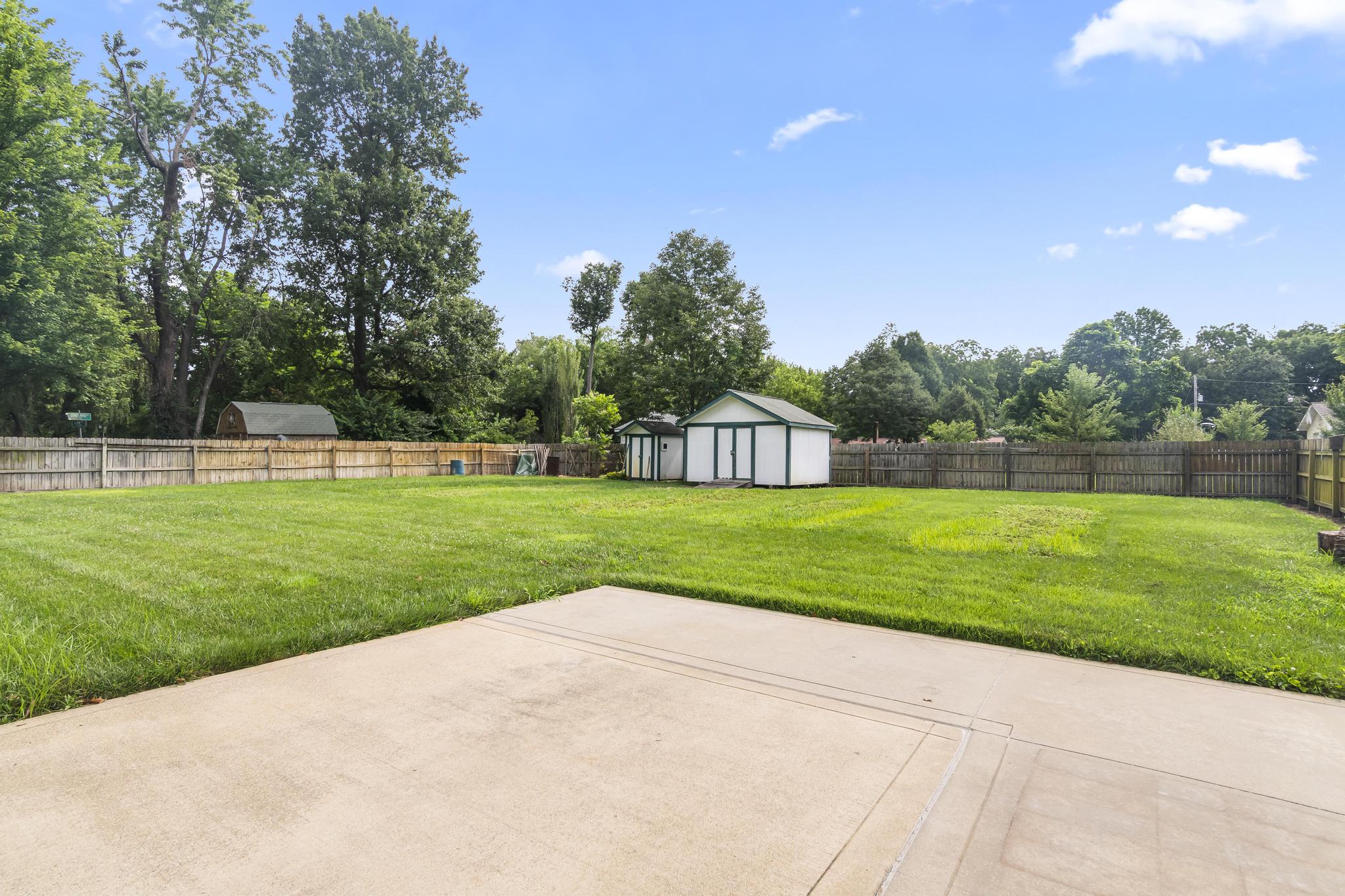 Exterior backyard features patio, fenced in yard and sheds