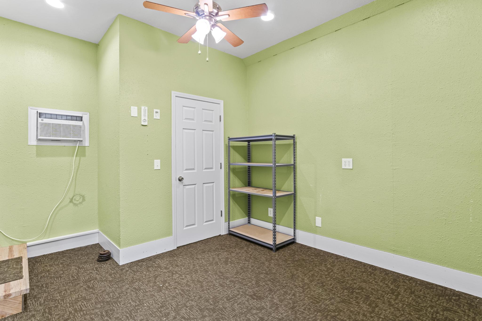 Garage office with carpeted flooring, ceiling fan wall mounted a/c unit