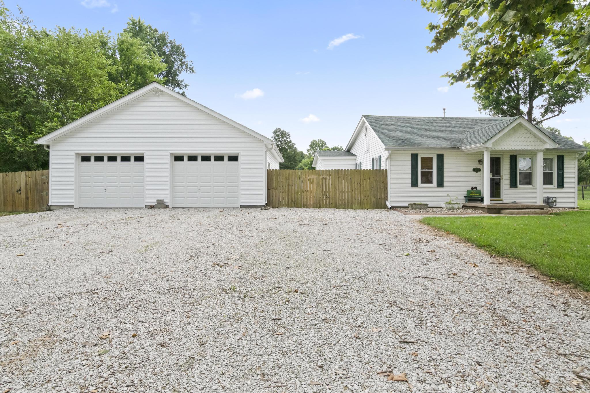 Front view of detached two bay garage and privacy fencing, with gravel driveway