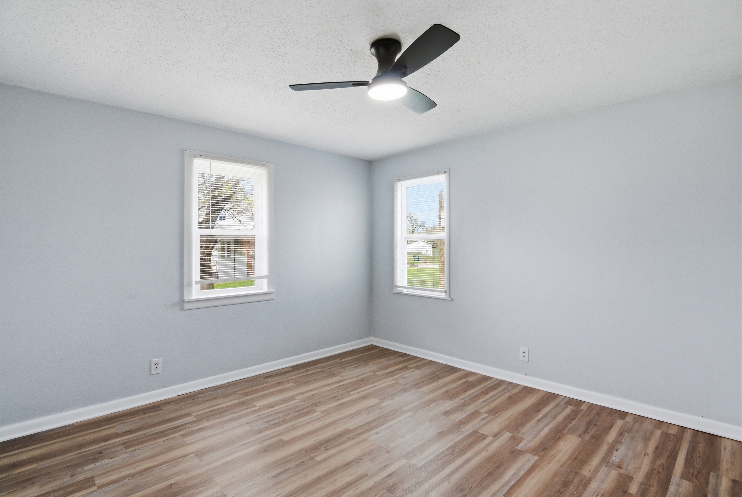 Freshly painted grey-walls, two windows with blinds, black ceiling fan and LVP wood-look flooring at1929 Beckwith St. Madison.