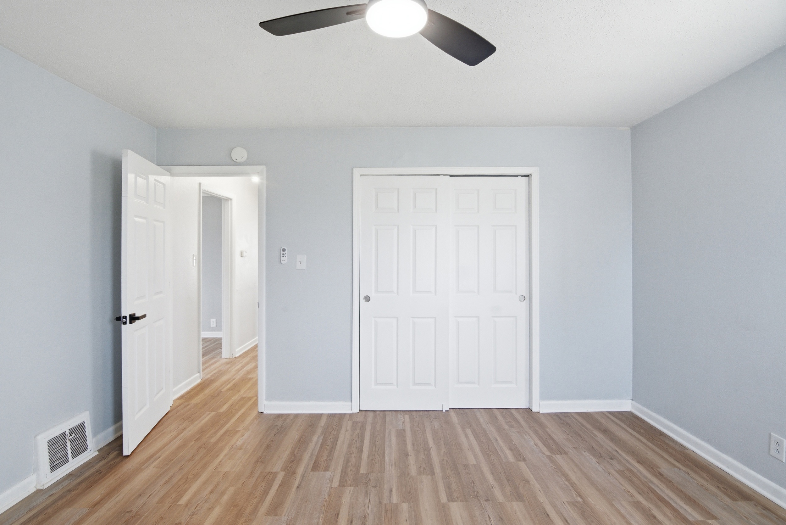 Double sliding closet doors, LVP flooring, and doorway to common hallway from primary bedroom area at 1929 Beckwith St. Madison.