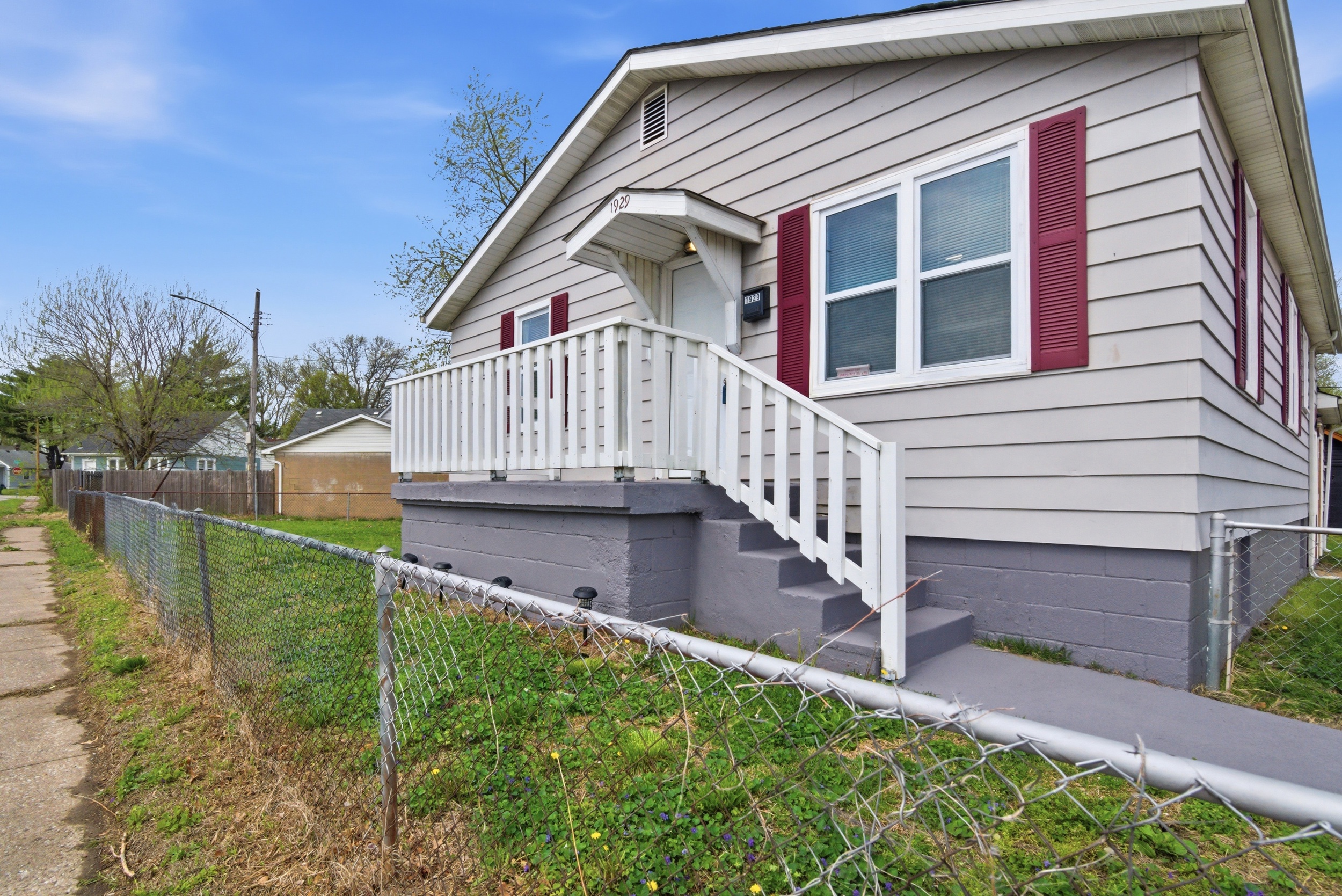 Side angle view of front exterior featuring porch and fence and sidewalk at 1929 Beckwith St. Madison.