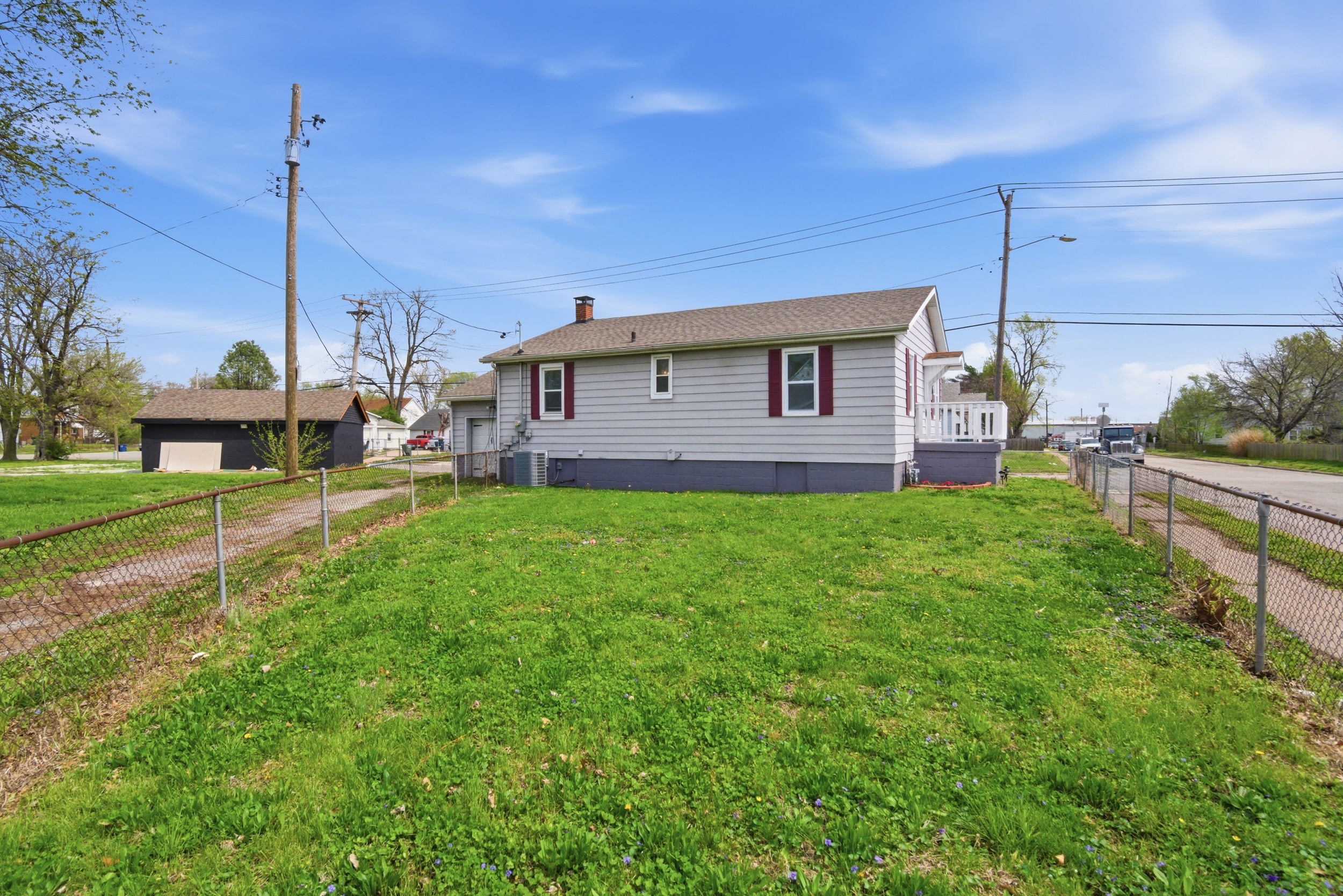 Side view of yard, shingled roof, fencing, alley and front porch at 1929 Beckwith St. Madison.