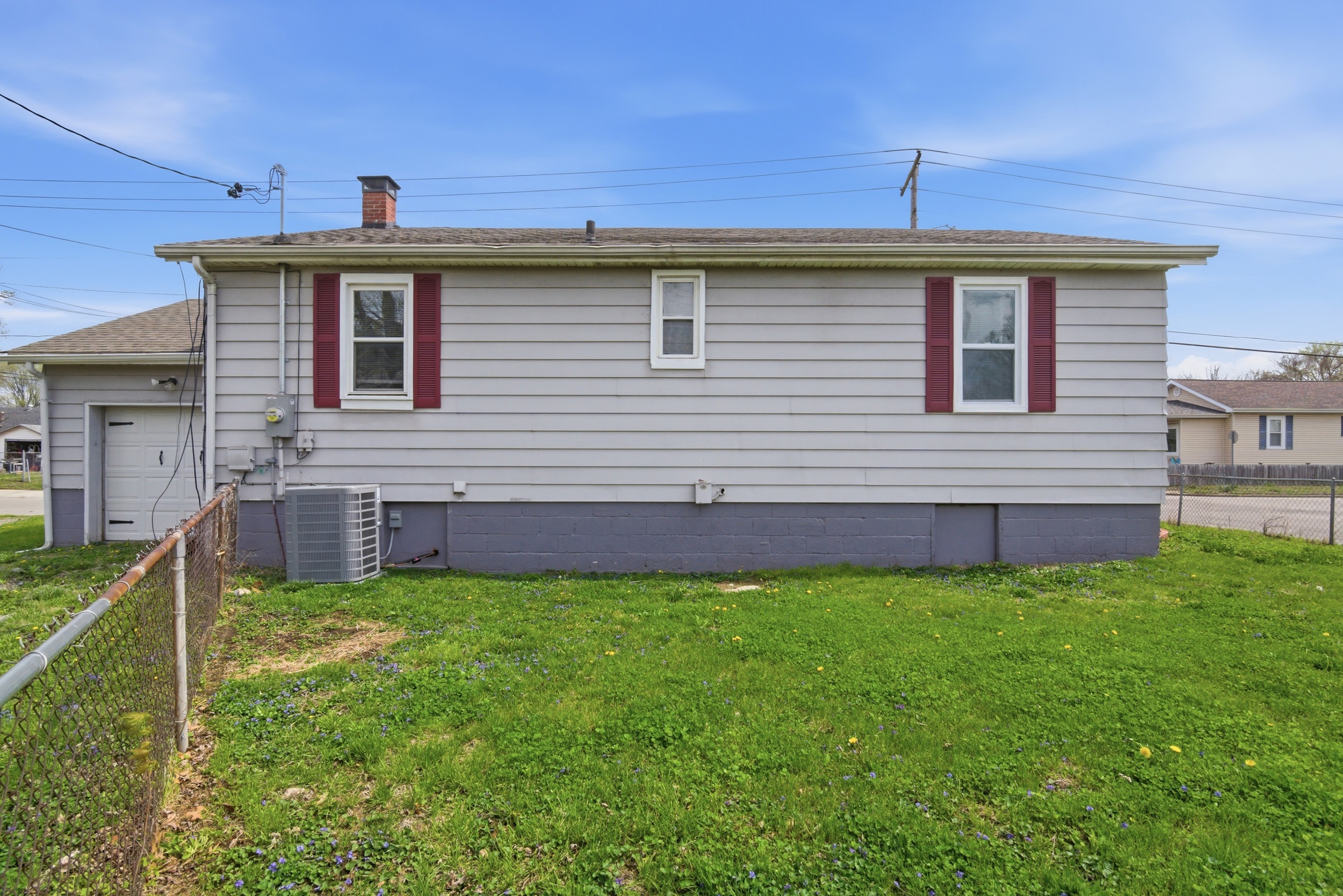 Side view of property exterior roof line, attached single car garage, and fenced yard at 1929 Beckwith St. Madison.