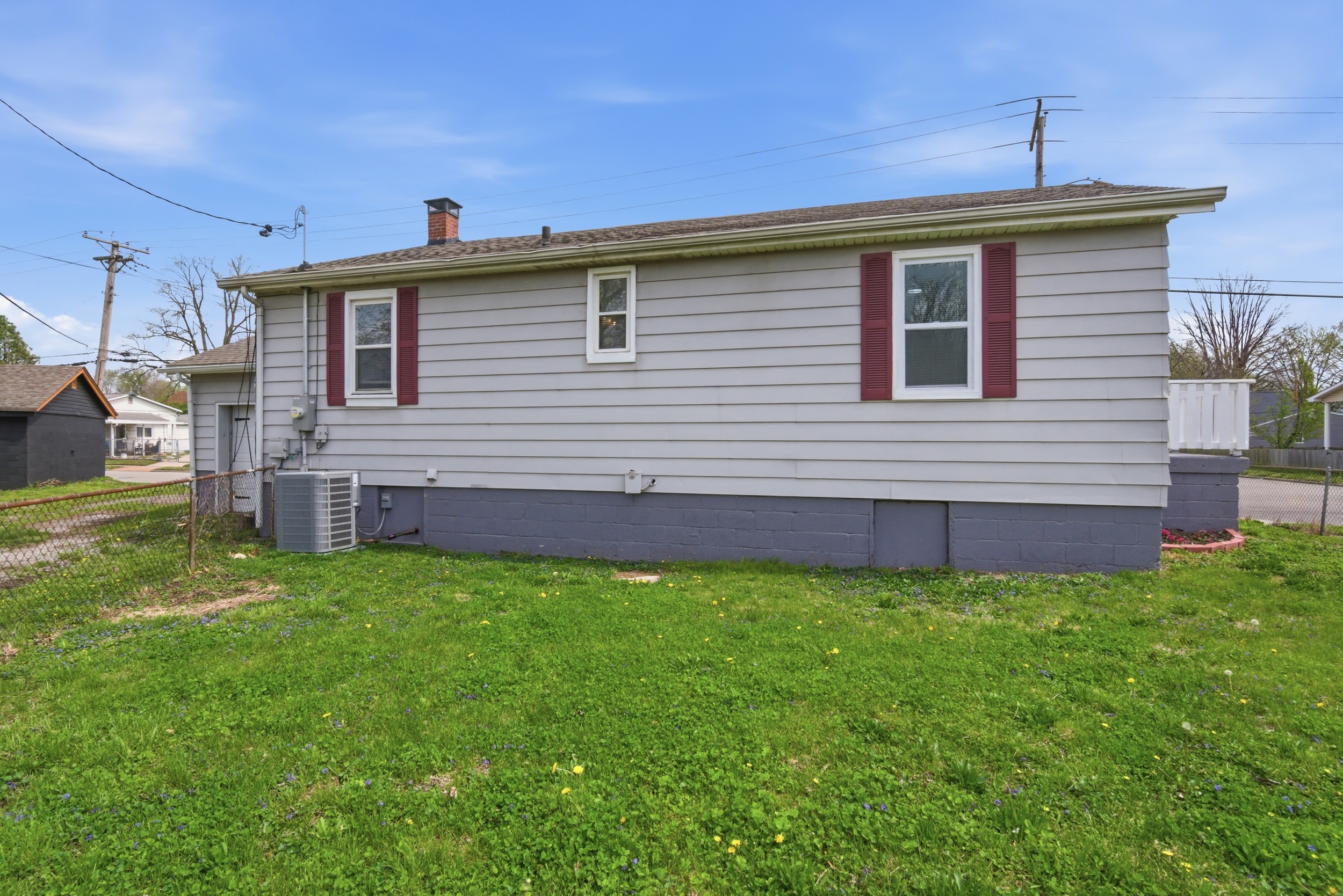 Back exterior view of home, gray siding, maroon shutters, new AC unit, and fenced yard at 1929 Beckwith St. Madison.
