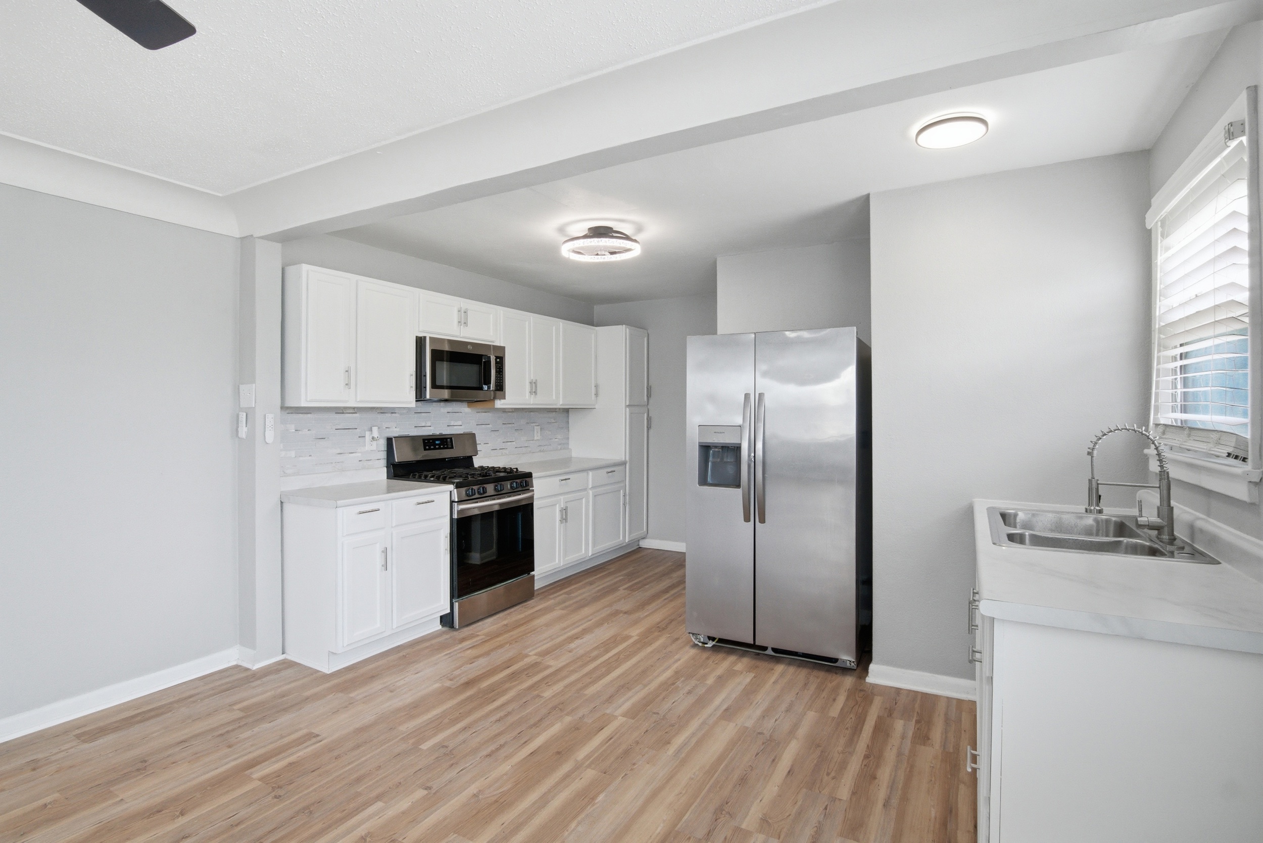 Stainless steel appliances, over-the-range microwave, gas stove and refrigerator, grey mosaic tile backsplash, and light countertops at 1929 Beckwith St. Madison.