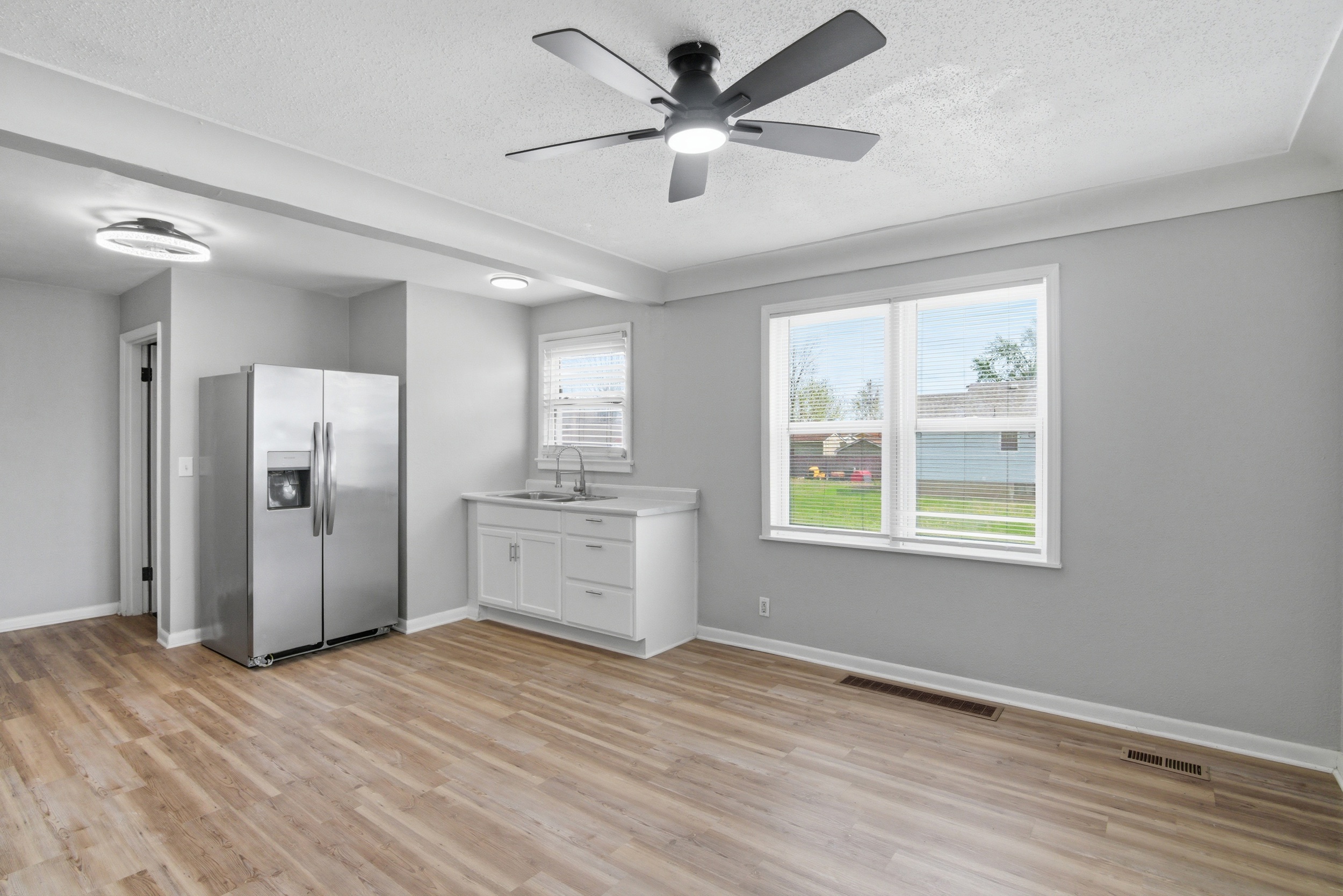 Updated Dining-Kitchen combo with large windows, coved ceilings, black ceiling fan, stainless appliance and wood-look laminate flooring at 1929 Beckwith St. Madison
